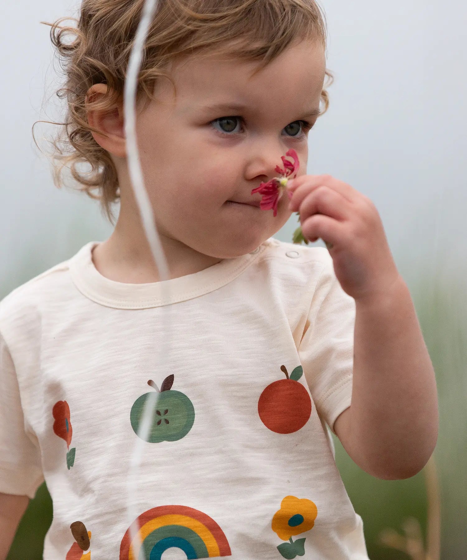 Close up of the nature illustrations on the front of the Little Green Radicals cream vintage style kids organic cotton t-shirt being worn.