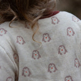 Close up of the penguin print on the Little Green Radicals organic cotton knitted cardigan with snow penguins design. Natural cream cardigan with penguins all over, maroon trim on the collar and hem line.