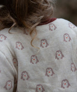 Close up of the penguin print on the Little Green Radicals organic cotton knitted cardigan with snow penguins design. Natural cream cardigan with penguins all over, maroon trim on the collar and hem line.