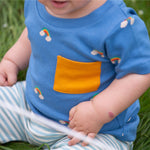 A close up of a child wearing the Little Green Radicals Kids' Organic T-shirt and Joggers Playset outfit in the  Blue Rainbows design. The t-shirt has a yellow pocket. 