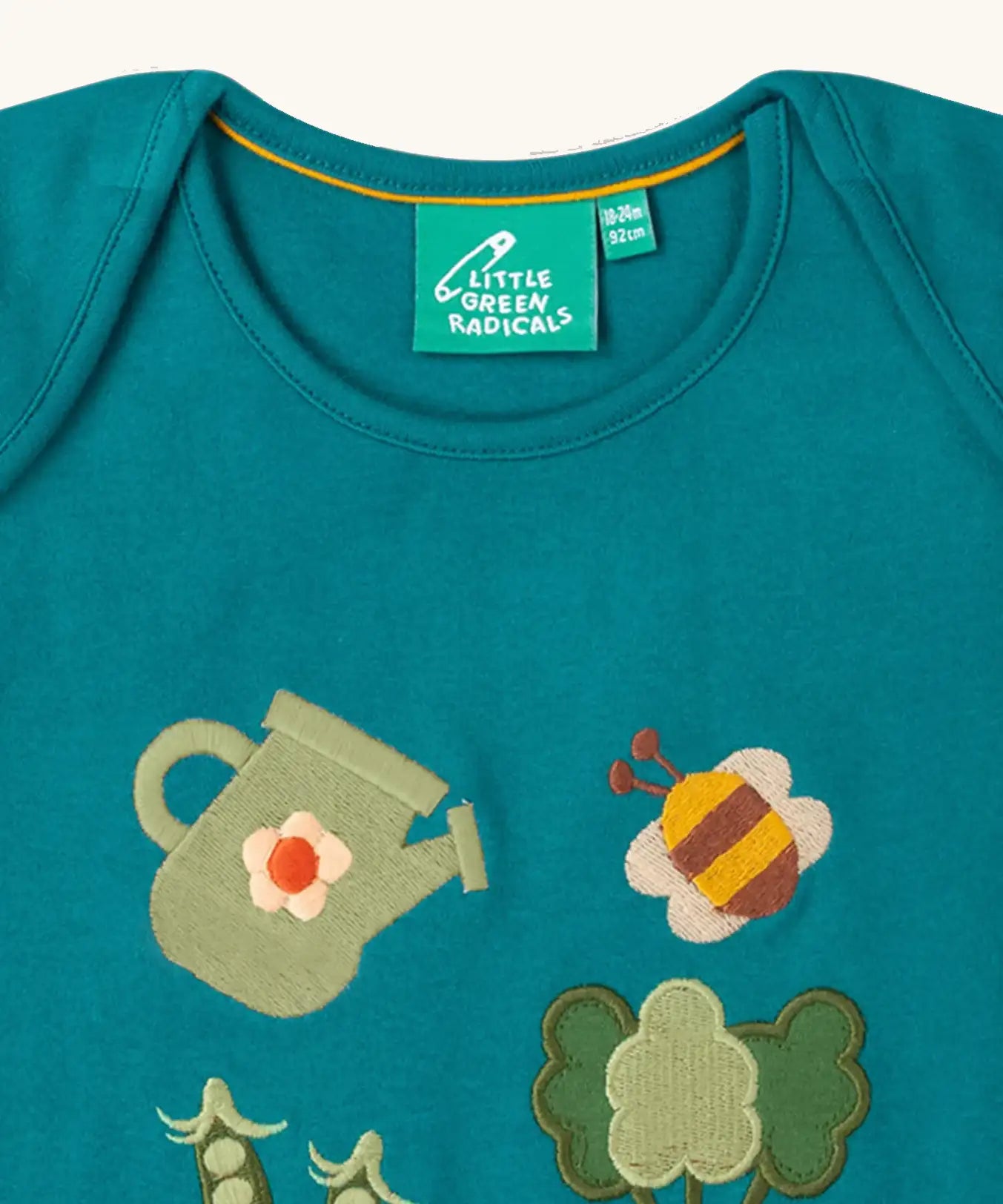Close up of envelope style neck on the Little Green Radicals Spring garden embroidered organic cotton green t-shirt. 