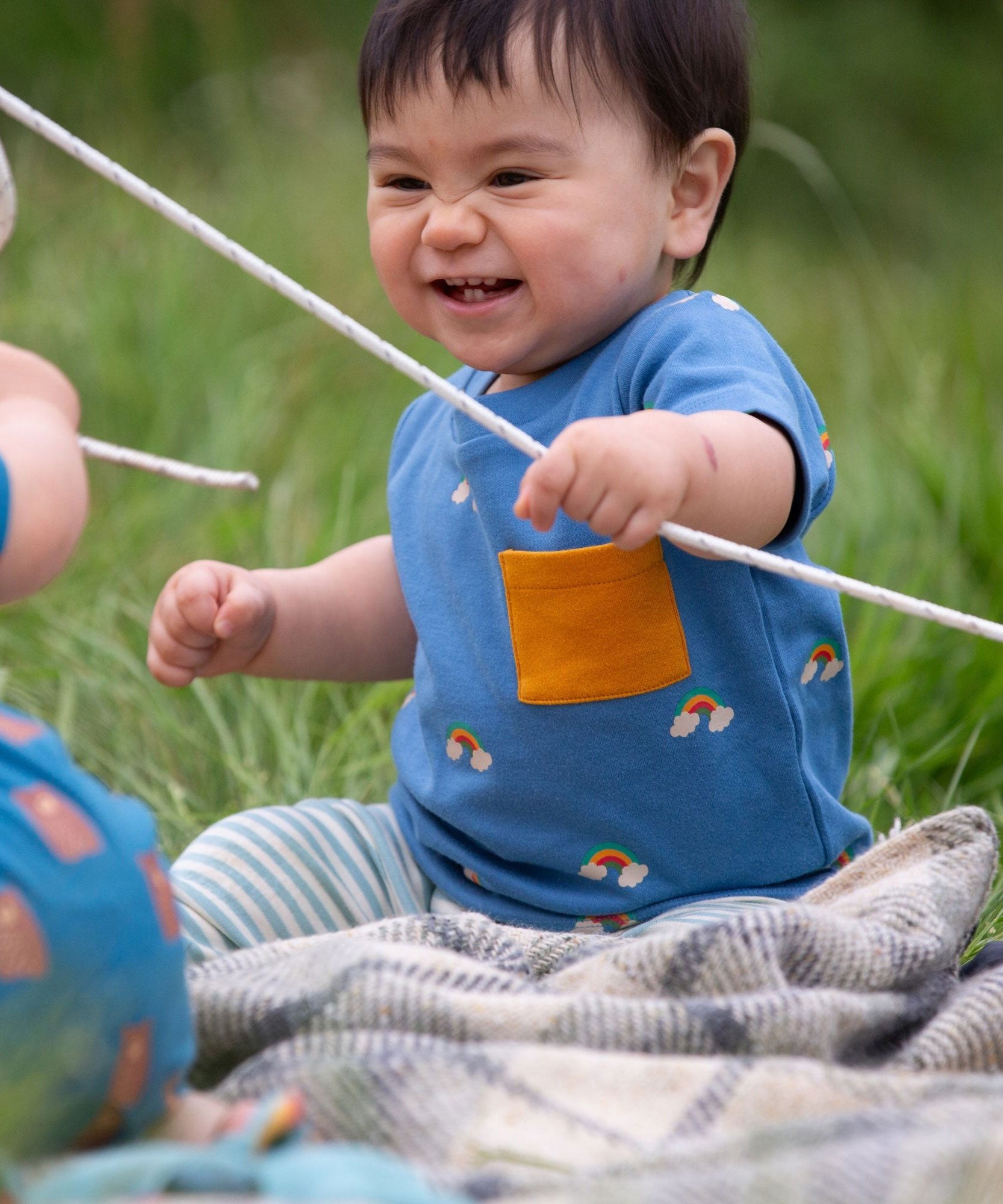 A child wearing the Little Green Radicals Kids' Organic T-shirt and Joggers Playset outfit in the  Blue Rainbows design. 
