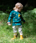 A child wearing the Little Green Radicals Kids' Organic Top and Joggers Playset in the Turquoise Rainbows design. This play set is part of a wide range of organic cotton clothing for children available here at Babipur. 