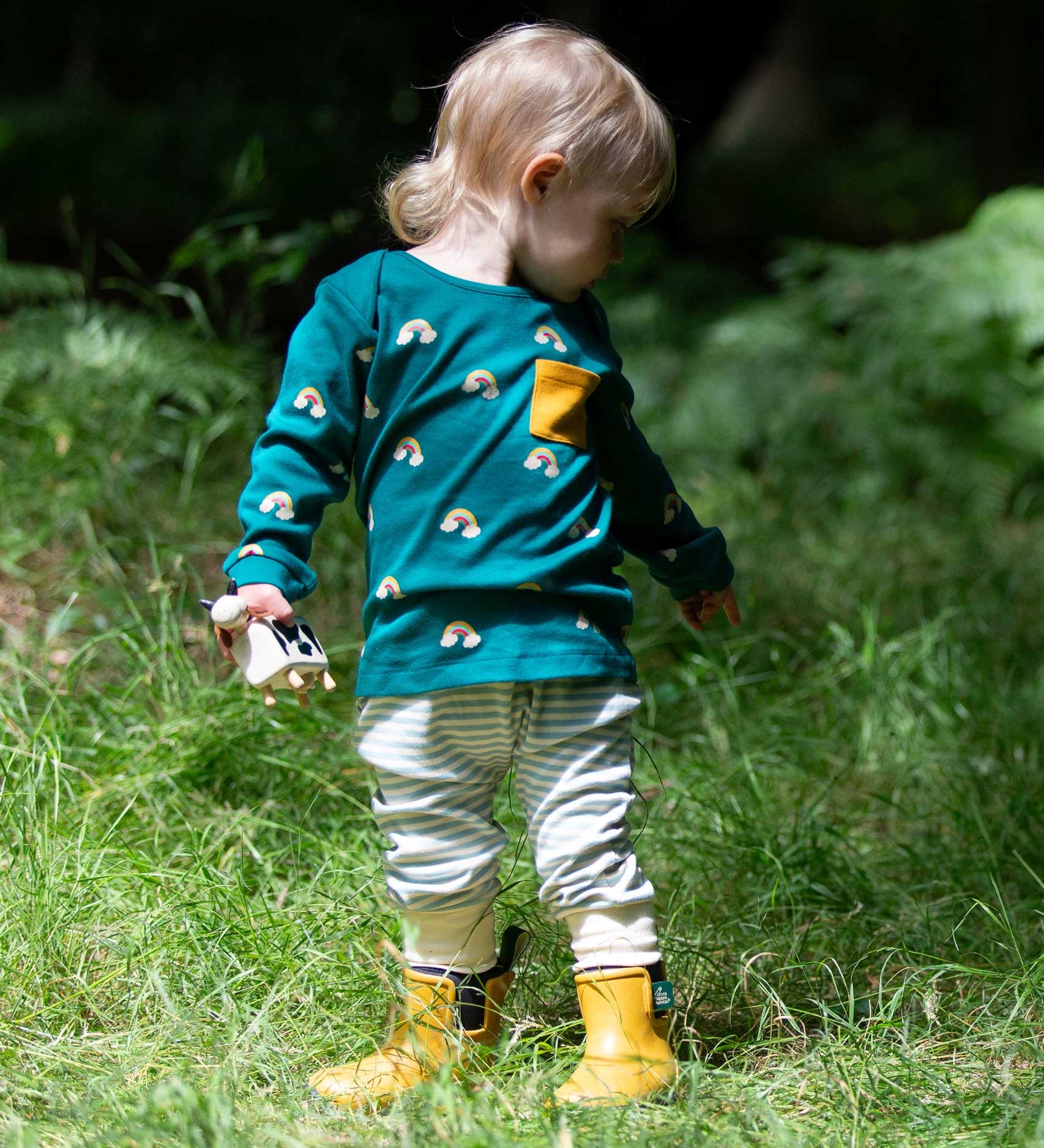 A child wearing the Little Green Radicals Kids' Organic Top and Joggers Playset in the Turquoise Rainbows design. This play set is part of a wide range of organic cotton clothing for children available here at Babipur. 
