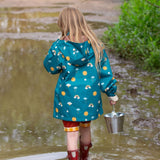 A child wearing the Little Green Radicals Child's Rainbow Days print Recycled Waterproof Raincoat facing away from the camera showing the back of the jacket