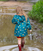 A child wearing the Little Green Radicals Child's Rainbow Days print Recycled Waterproof Raincoat facing away from the camera showing the back of the jacket