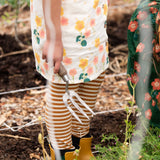 Close up of child's legs wearing the Little Green Radicals apricot gold striped organic cotton leggings.