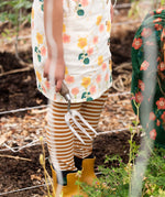 Close up of child's legs wearing the Little Green Radicals apricot gold striped organic cotton leggings.