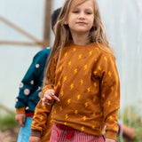 Child wearing the Little Green Radicals kids yellow lightning repeat print organic cotton sweatshirt with red pinstripe shorts.
