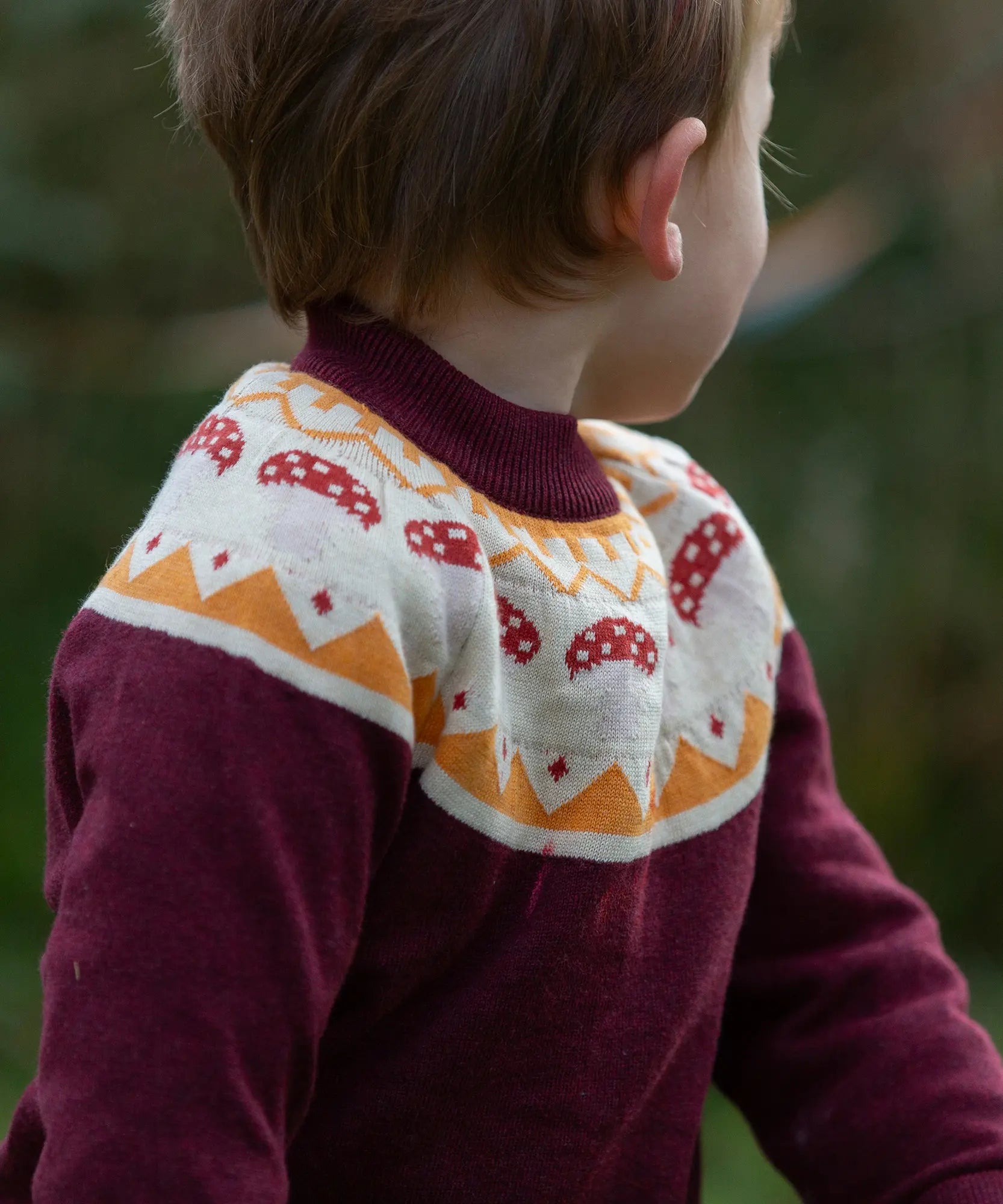 Close up of child wearing the Little Green Radicals knitted organic cotton jumper with a mushroom Fair Isle design.