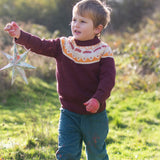Child wearing the Little Green Radicals knitted organic cotton jumper with a mushroom Fair Isle design with green corduroy trousers. 