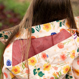 mesh lined hood on the Little Green Radicals flower meadow recycled waterproof kids raincoat with a child wearing it.