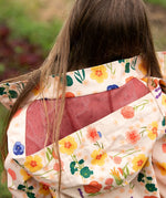 mesh lined hood on the Little Green Radicals flower meadow recycled waterproof kids raincoat with a child wearing it.