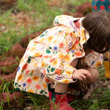 The side of a child wearing the Little Green Radicals flower meadow recycled waterproof kids raincoat.
