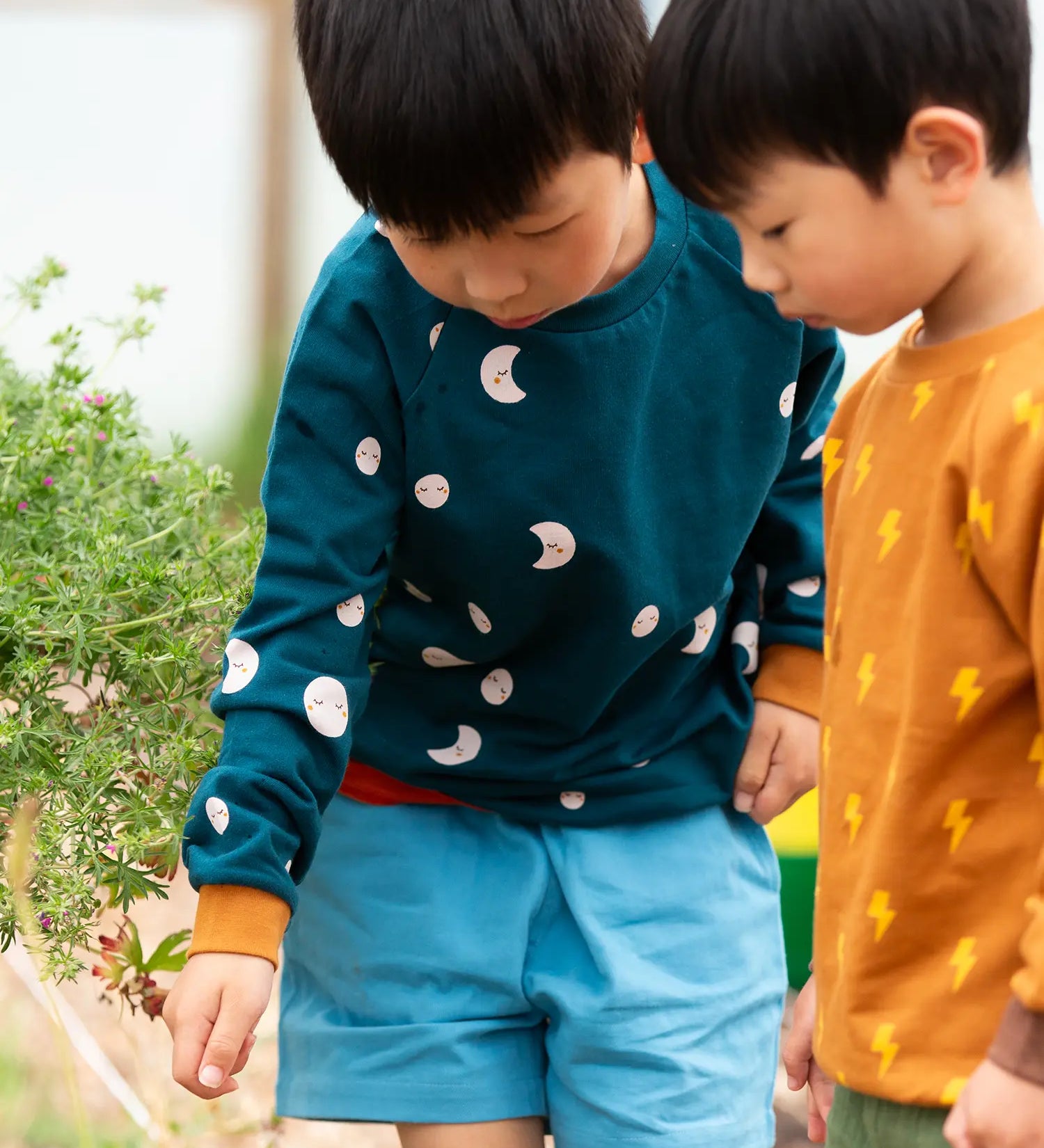 Child wearing the Little Green Radicals midnight moon print blue raglan organic cotton children's sweatshirt.