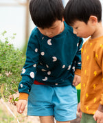 Child wearing the Little Green Radicals midnight moon print blue raglan organic cotton children's sweatshirt.