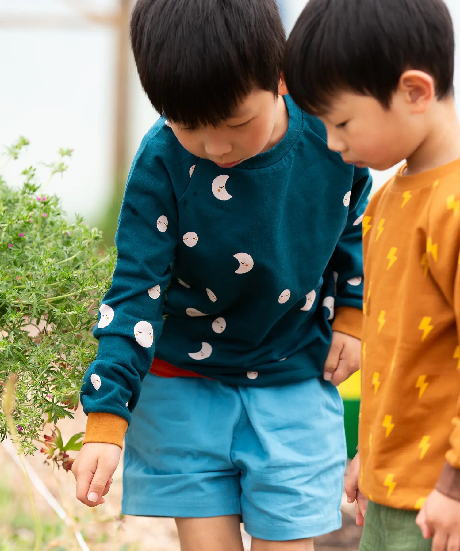 Child wearing the Little Green Radicals midnight moon print blue raglan organic cotton children's sweatshirt.