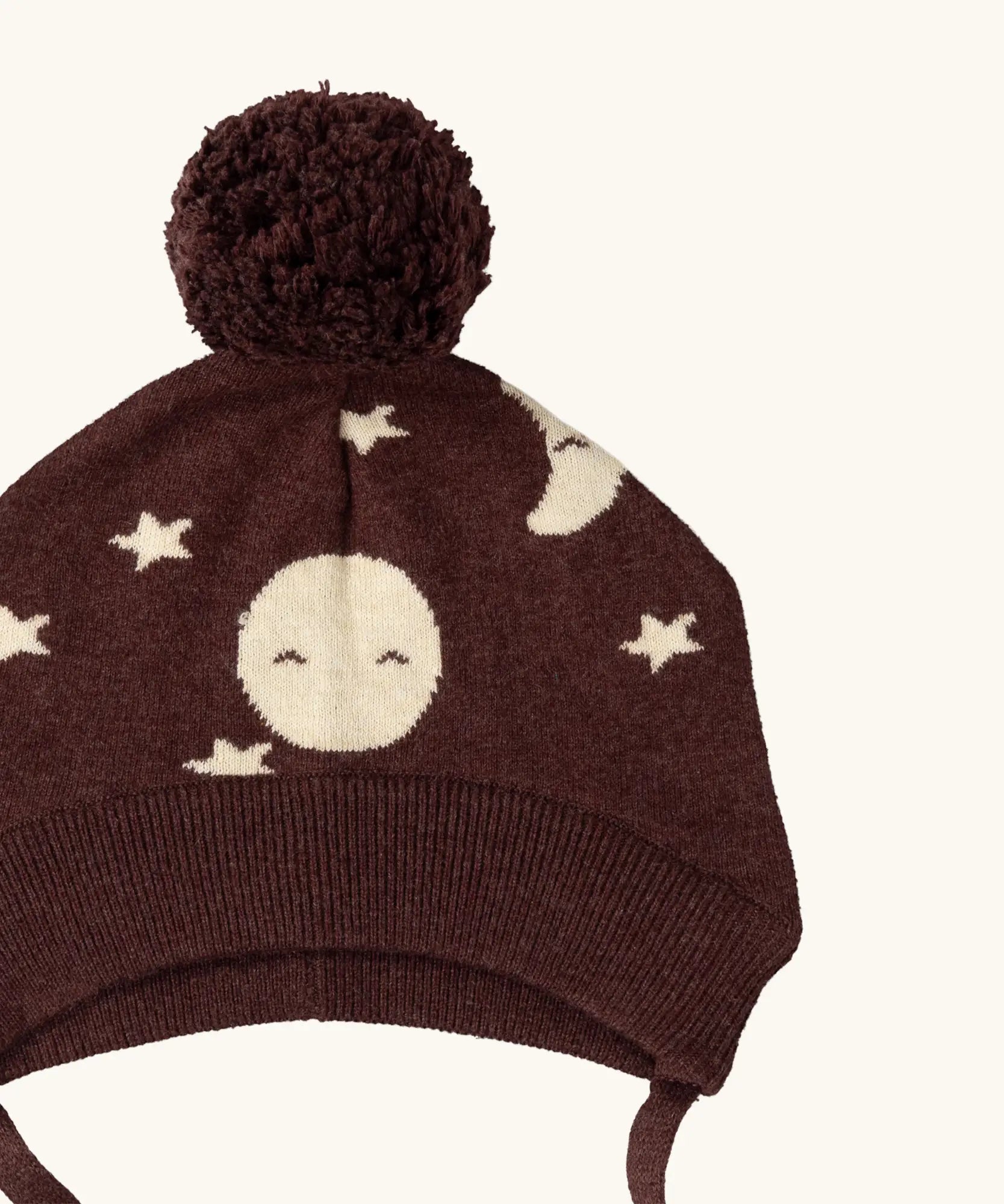 Close up of the bobble on the Little Green Radicals brown organic cotton moon knitted bobble hat with chin strap ties.