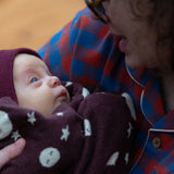 Baby wrapped up in a Little Green Radicals moon brown knitted organic cotton baby blanket.