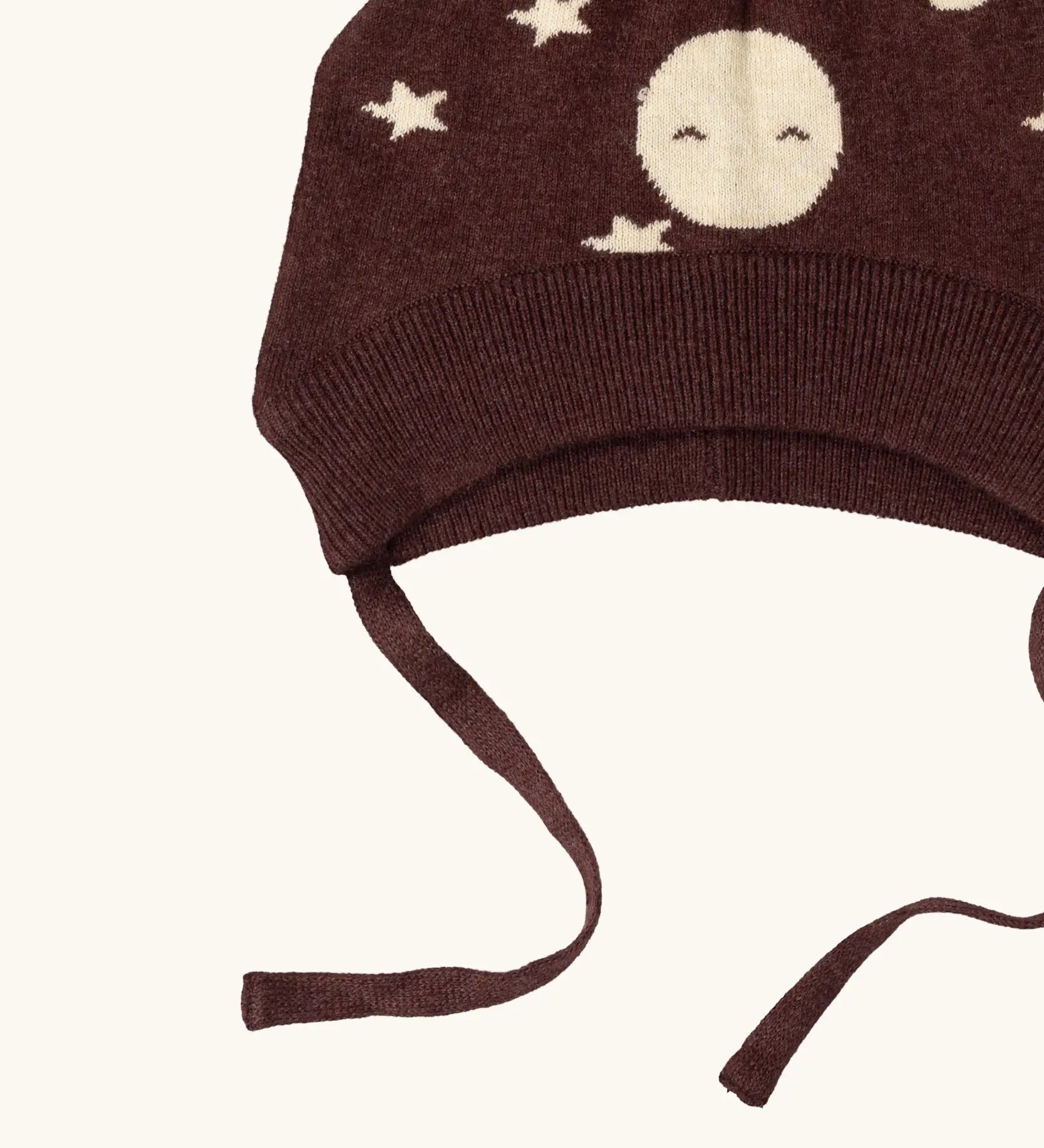 Close up of the chin strap ties on the Little Green Radicals brown organic cotton moon knitted bobble hat.