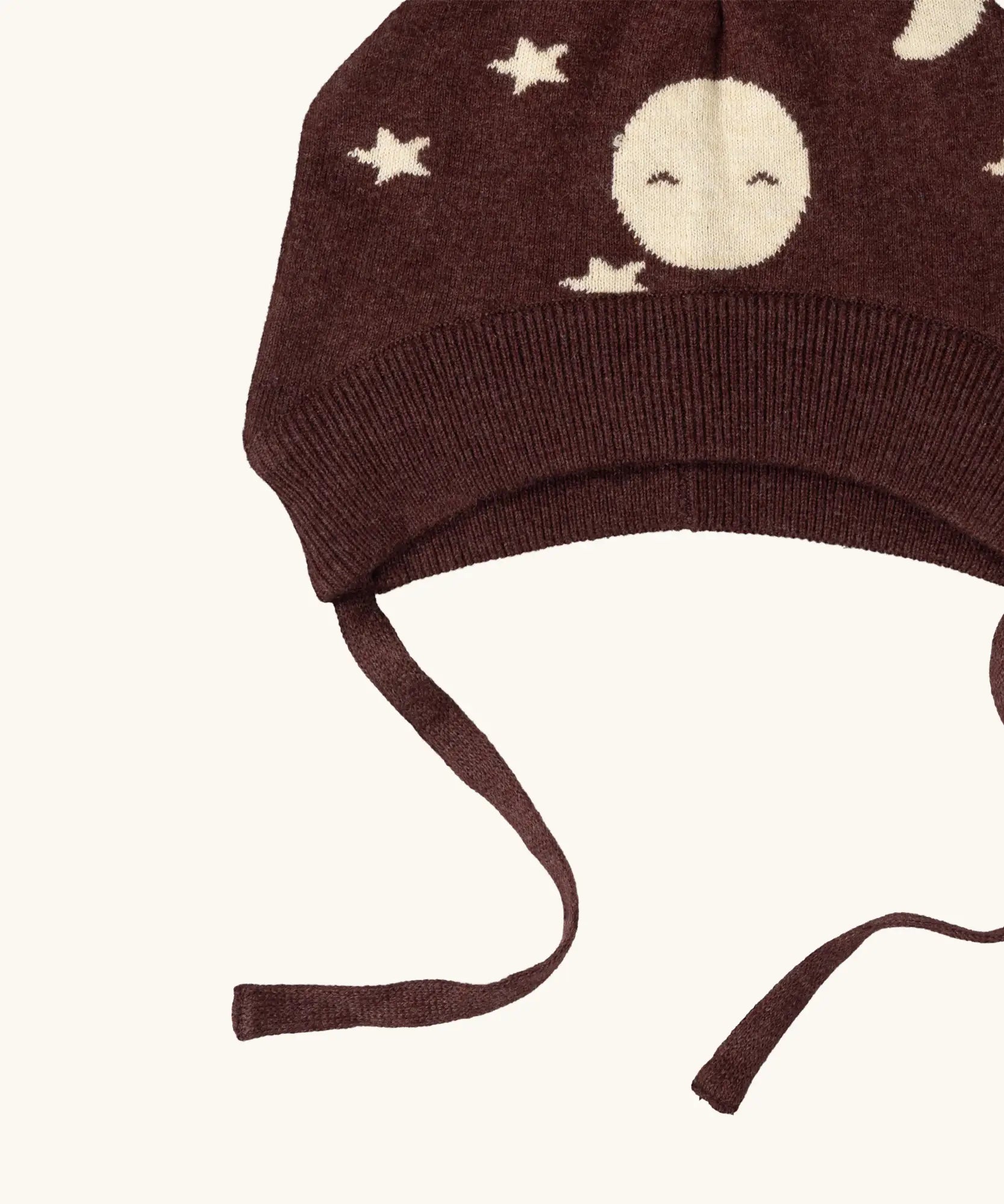 Close up of the chin strap ties on the Little Green Radicals brown organic cotton moon knitted bobble hat.