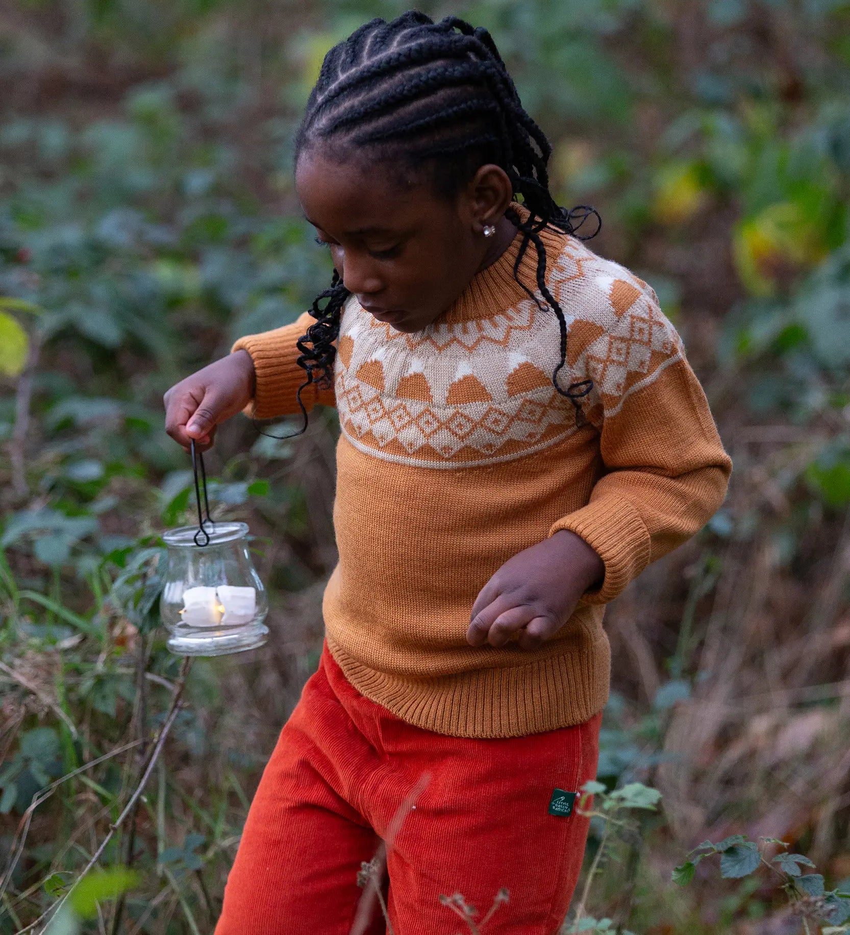 Child wearing the Little Green Radicals mountain Fair Isle snuggly woollen jumper in yellow gold with orange corduroy trousers.
