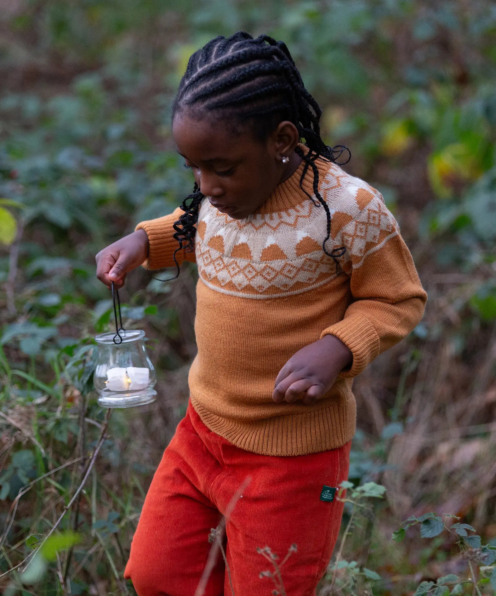 Child wearing the Little Green Radicals mountain Fair Isle snuggly woollen jumper in yellow gold with orange corduroy trousers.