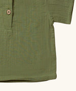 Close up of the hemline on the Little Green Radicals Muslin Loose Fit Short Sleeve Henley Top in a  Chive Green colour way.
