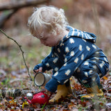 Child wearing a Little Green Radicals navy blue penguins hooded reversible snug suit with yellow gold wellington boots.