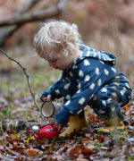 Child wearing a Little Green Radicals navy blue penguins hooded reversible snug suit with yellow gold wellington boots.
