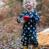 Child wearing a Little Green Radicals navy blue penguins hooded reversible snug suit with yellow gold ankle wellington boots. 