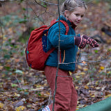 A child walking through a forest wearing the Little Green Radicals dark nights corduroy backpack on their back. A 100% organic cotton backpack in a navy and red corduroy style with a starry night design. Features a handle on the top for easy carrying a front pocket and 2 bottle holders. This children's bag is a part of a wide range of organic cotton clothing and accessories for children available here at Babipur. 
