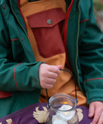 Child wearing a Little Green Radicals olive green recycled waterproof 3 in 1 coat with yellow waterproof dungarees underneath.