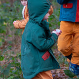 Child wearing a Little Green Radicals olive green recycled waterproof 3 in 1 coat with yellow waterproof dungarees underneath.