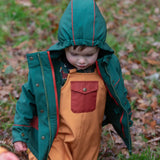 Child wearing a Little Green Radicals olive green recycled waterproof 3 in 1 coat with yellow waterproof dungarees underneath.