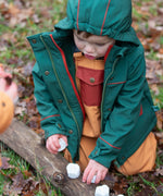 Child wearing a Little Green Radicals olive green recycled waterproof 3 in 1 coat with yellow waterproof dungarees underneath.
