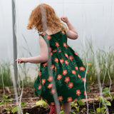 Back of the Little Green Radicals green orange blooms repeat print reversible pinny kids dress being worn.