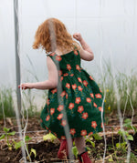 Back of the Little Green Radicals green orange blooms repeat print reversible pinny kids dress being worn.