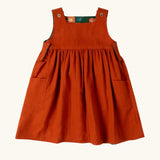 Little Green Radicals green orange blooms repeat print reversible pinny kids dress shown on the orange side..