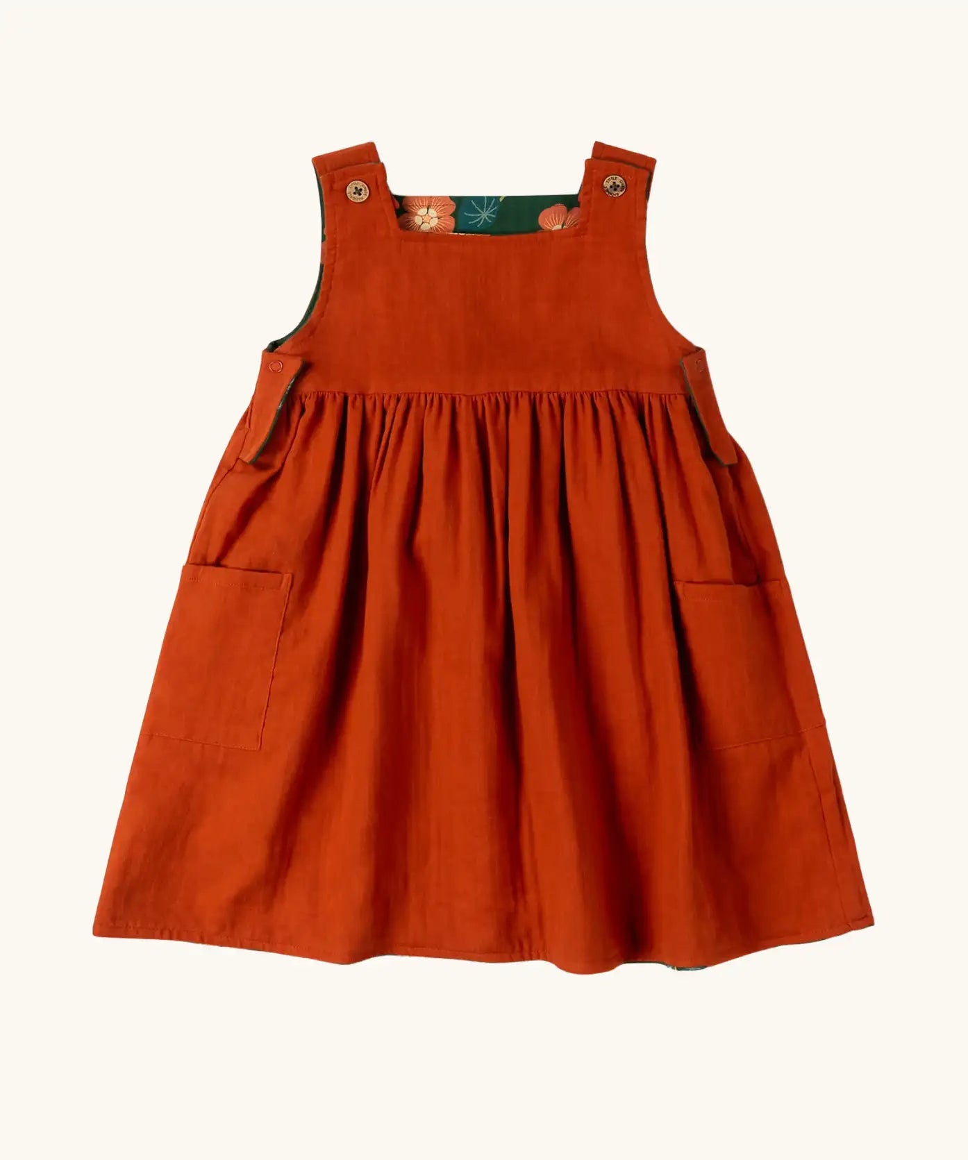Little Green Radicals green orange blooms repeat print reversible pinny kids dress shown on the orange side..
