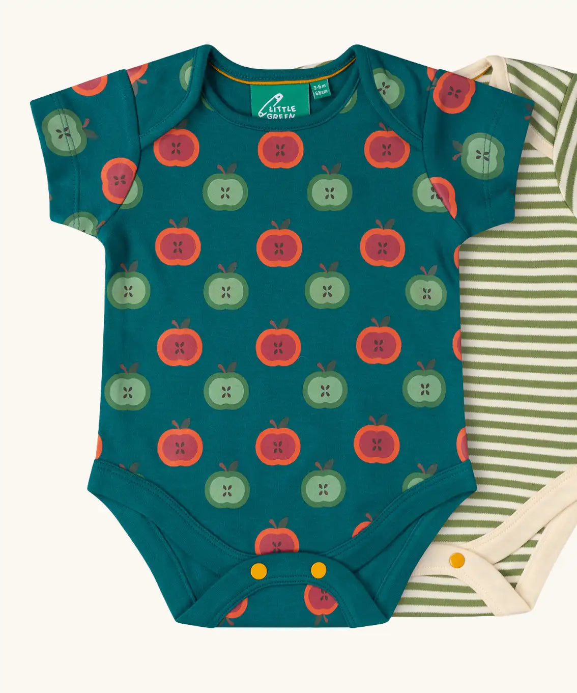 Close up of the apple print vest from the Little Green Radicals short sleeve baby bodysuit 2 pack. A repeat red and green apples print on a dark green background.