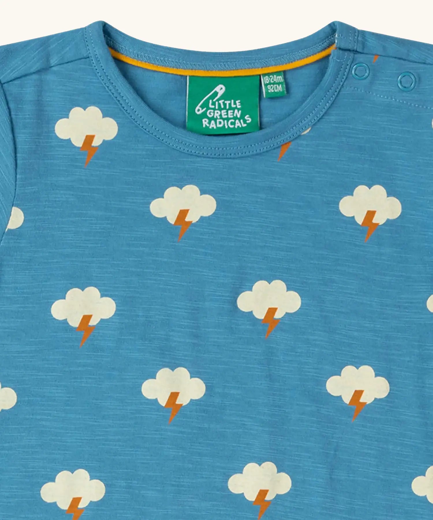 Close up of the poppered neck closure on the Little Green Radicals blue all weather repeat print organic cotton short sleeve t-shirt.