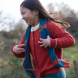 Child wearing Little Green Radicals tulips knitted blue scarf. Blue scarf with red tulips.