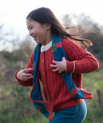 Child wearing Little Green Radicals tulips knitted blue scarf. Blue scarf with red tulips.