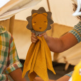A child holding the Little Green Radicals Golden yellow Lion Organic Cotton Baby Comforter Toy up to the camera.