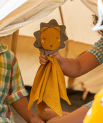 A child holding the Little Green Radicals Golden yellow Lion Organic Cotton Baby Comforter Toy up to the camera.