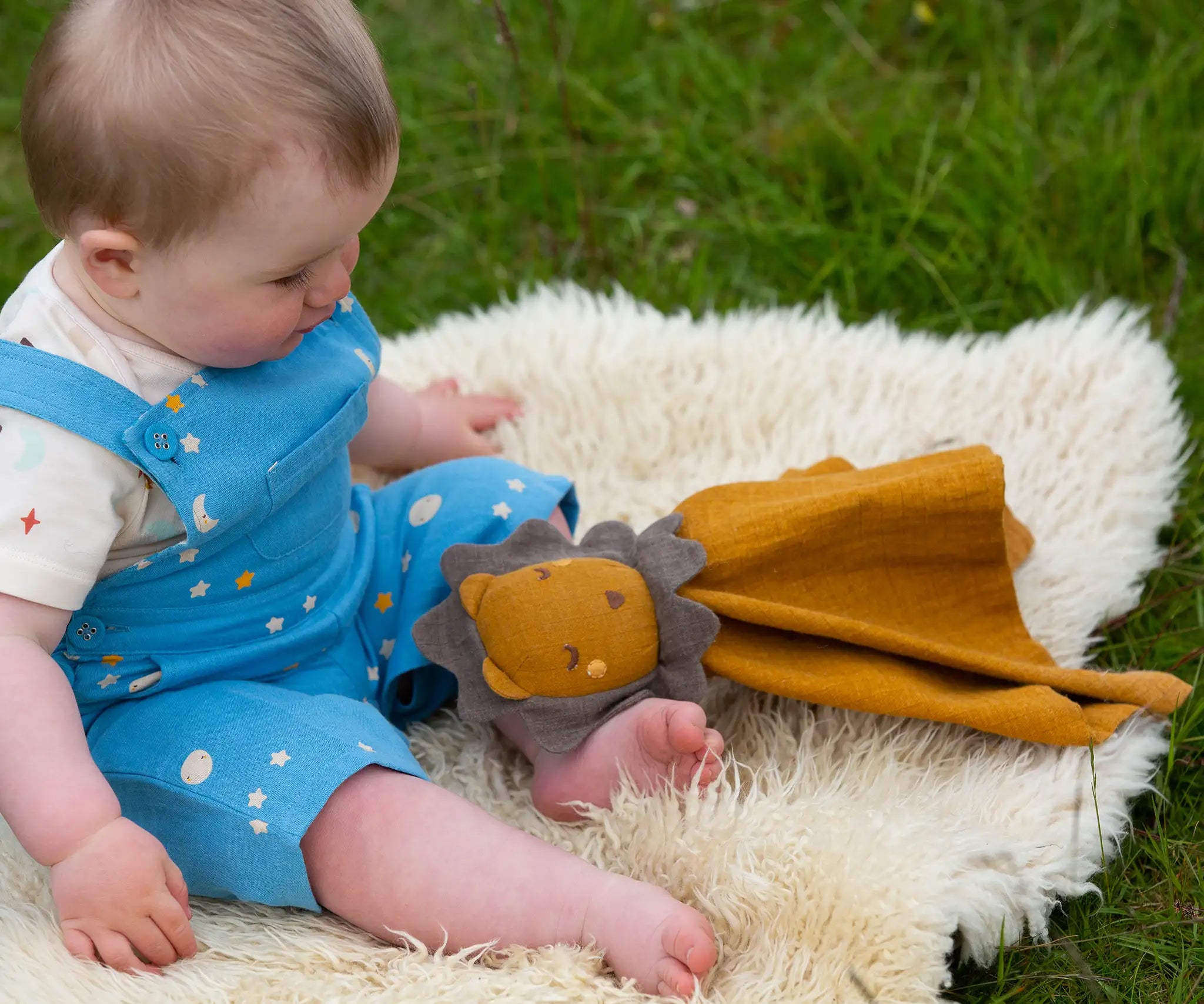 A baby playing with the Little Green Radicals Golden yellow Lion Organic Cotton Baby Comforter Toy.