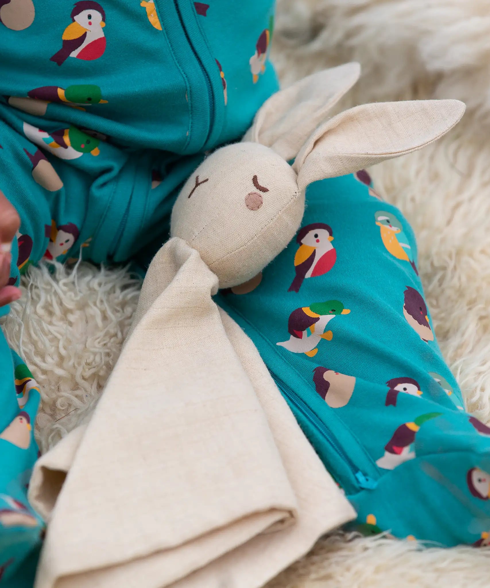 A close up of the Little Green Radicals rabbit organic cotton baby comforter toy on a baby's lap.