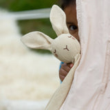 A child playing peek-a-boo holding the Little Green Radicals rabbit organic cotton baby comforter toy in front of them.