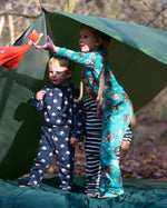 Children standing outside a tent in the forest. They are all wearing Little Green Radicals organic cotton pyjamas. One is wearing a pair with the Winter Rabbit on them, one in wearing navy and white striped design and the third is wearing the sleeping sheep print. Little green Radicals have a wide range of organic cotton, Fairtrade children's clothing an outerwear available here at Babipur.